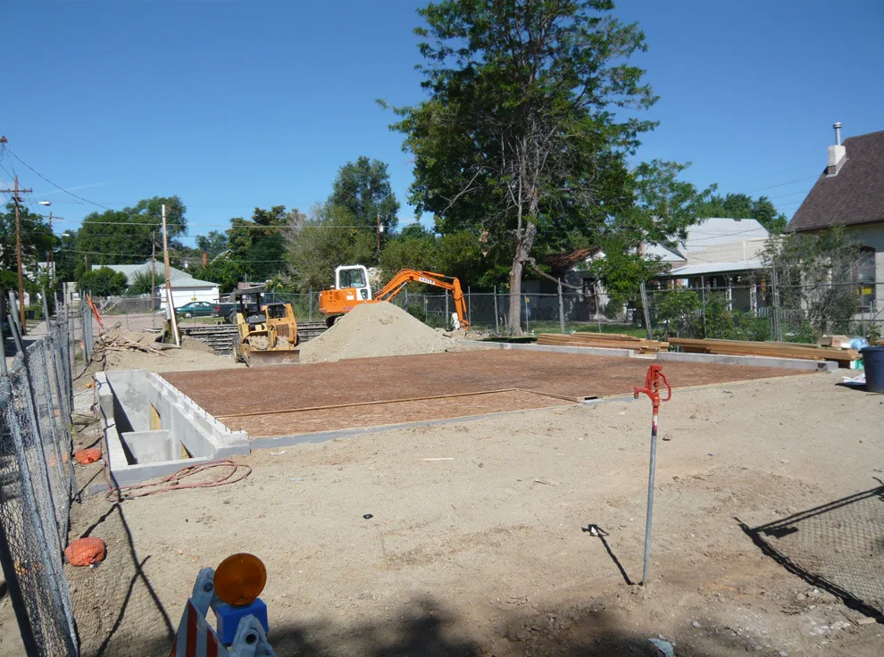 Concrete foundation and construction groundwork for a building project with excavation equipment on site.
