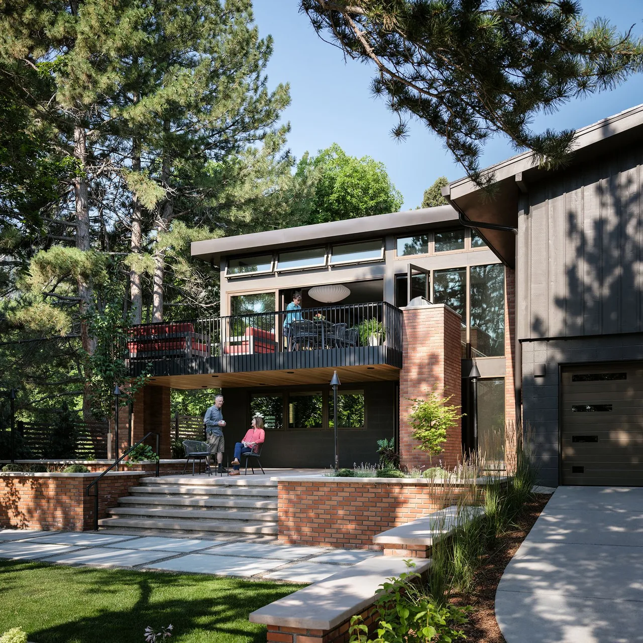 The V|O Residence features a brick courtyard with an elevated balcony and large windows under a sloped roof.
