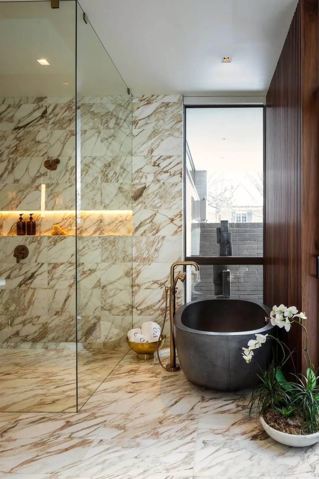 Marble-finished bathroom features a standalone tub, glass shower enclosure, and floor-to-ceiling window.