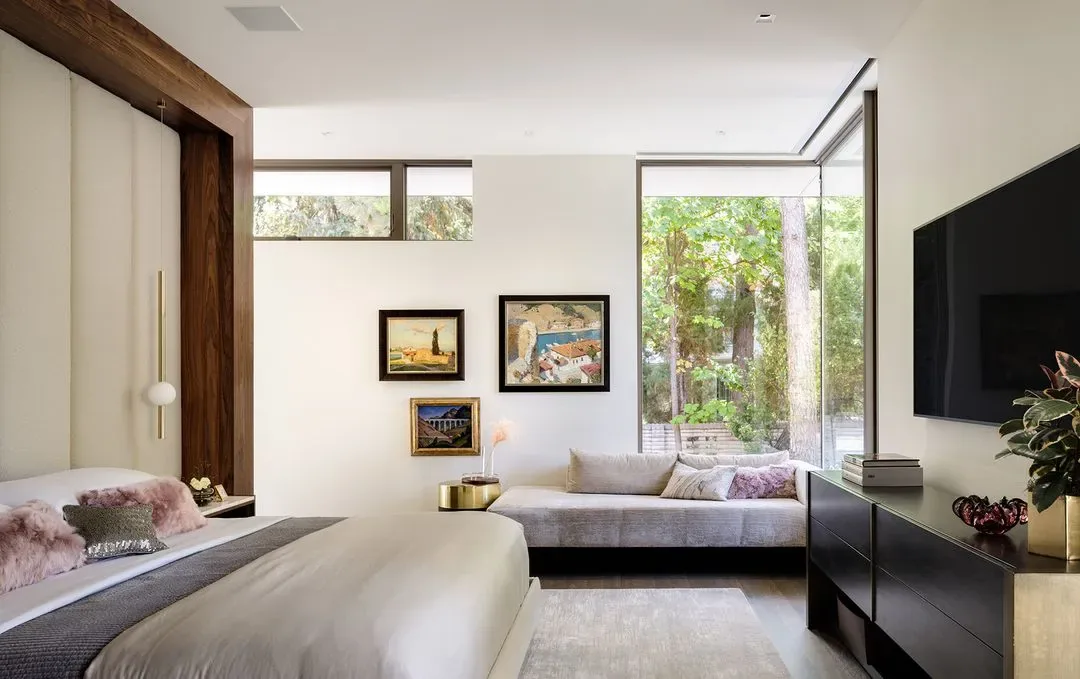 Bedroom featuring floor-to-ceiling glazing, an upholstered bench, and minimalist decor with framed artwork.
