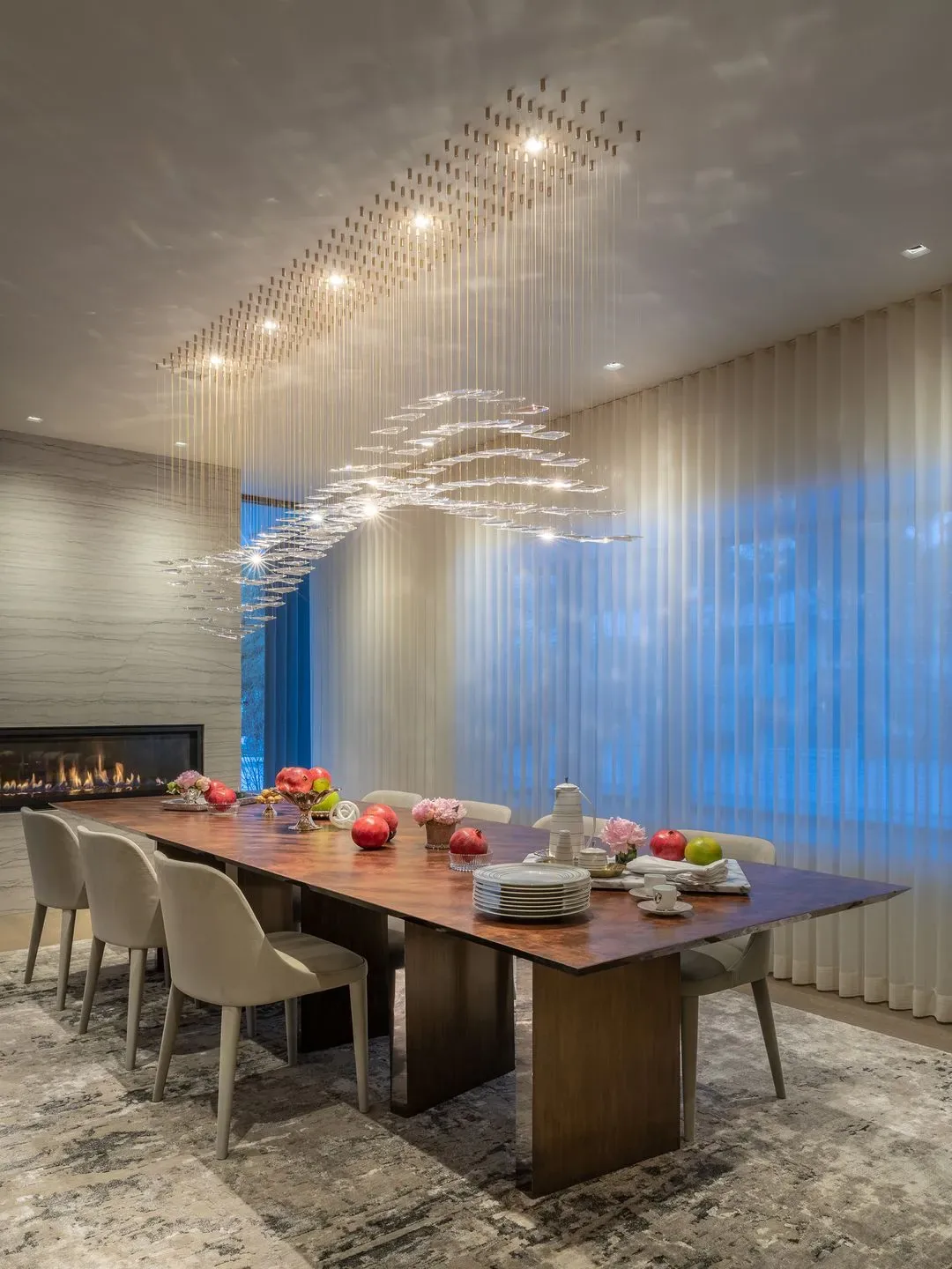 Dining room features a large wooden table surrounded by upholstered chairs and a decorative hanging light fixture, with a fireplace on the side wall.