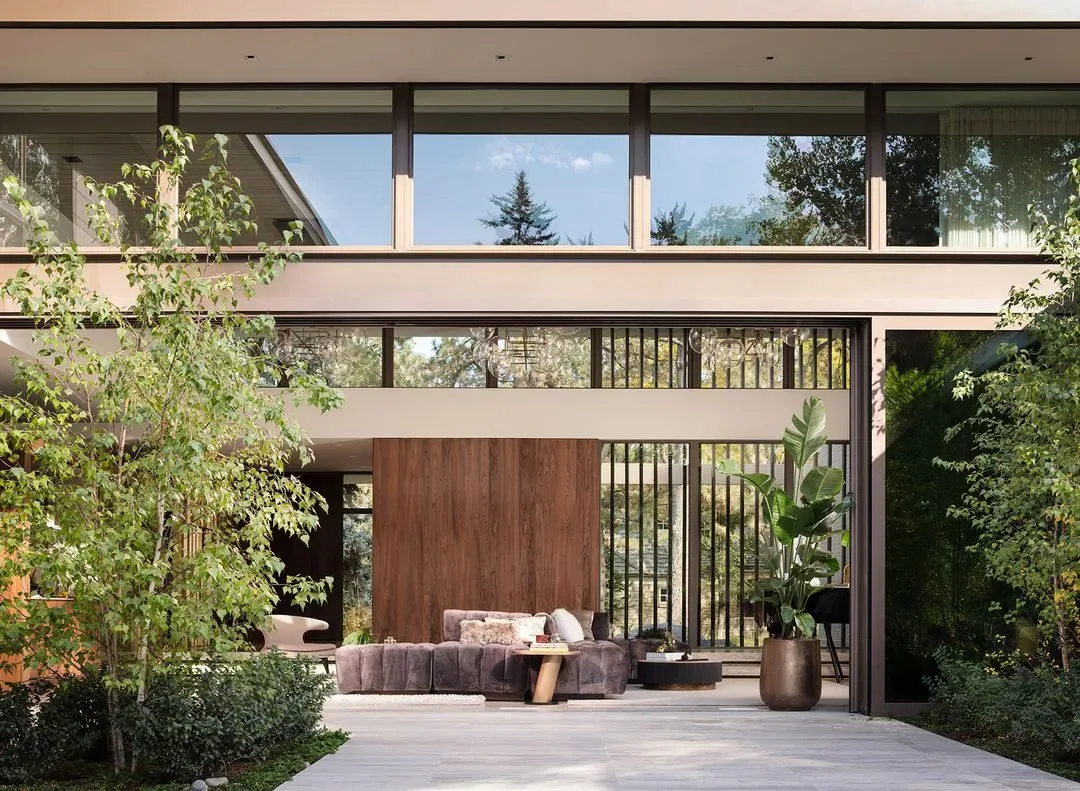 Living room with floor-to-ceiling sliding glass doors opens to landscaped exterior at Kennedy Residence.