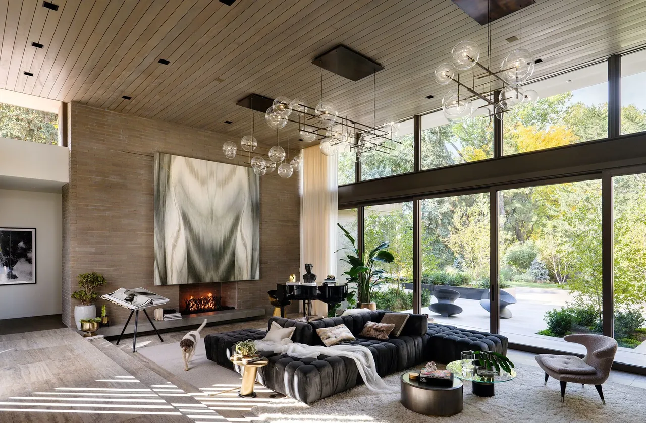 Living room featuring floor-to-ceiling glazing, a fireplace, and modern furniture overlooking an outdoor patio.
