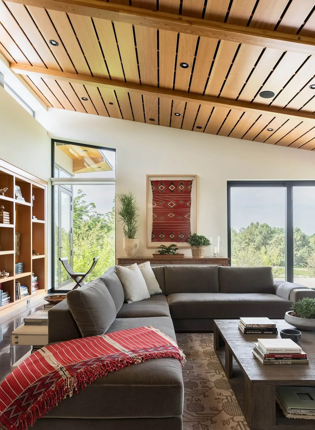 The Cherry Residence living room features a sectional sofa, wood-paneled ceiling with beams, and large window views of the garden.
