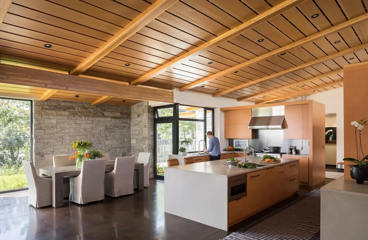 The Cherry Residence kitchen features a wood paneled ceiling and stone accent wall, highlighting natural materials.