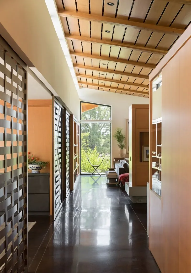 Hallway in Cherry Residence features a wood-paneled ceiling with beams and woven wood privacy screens along one side.