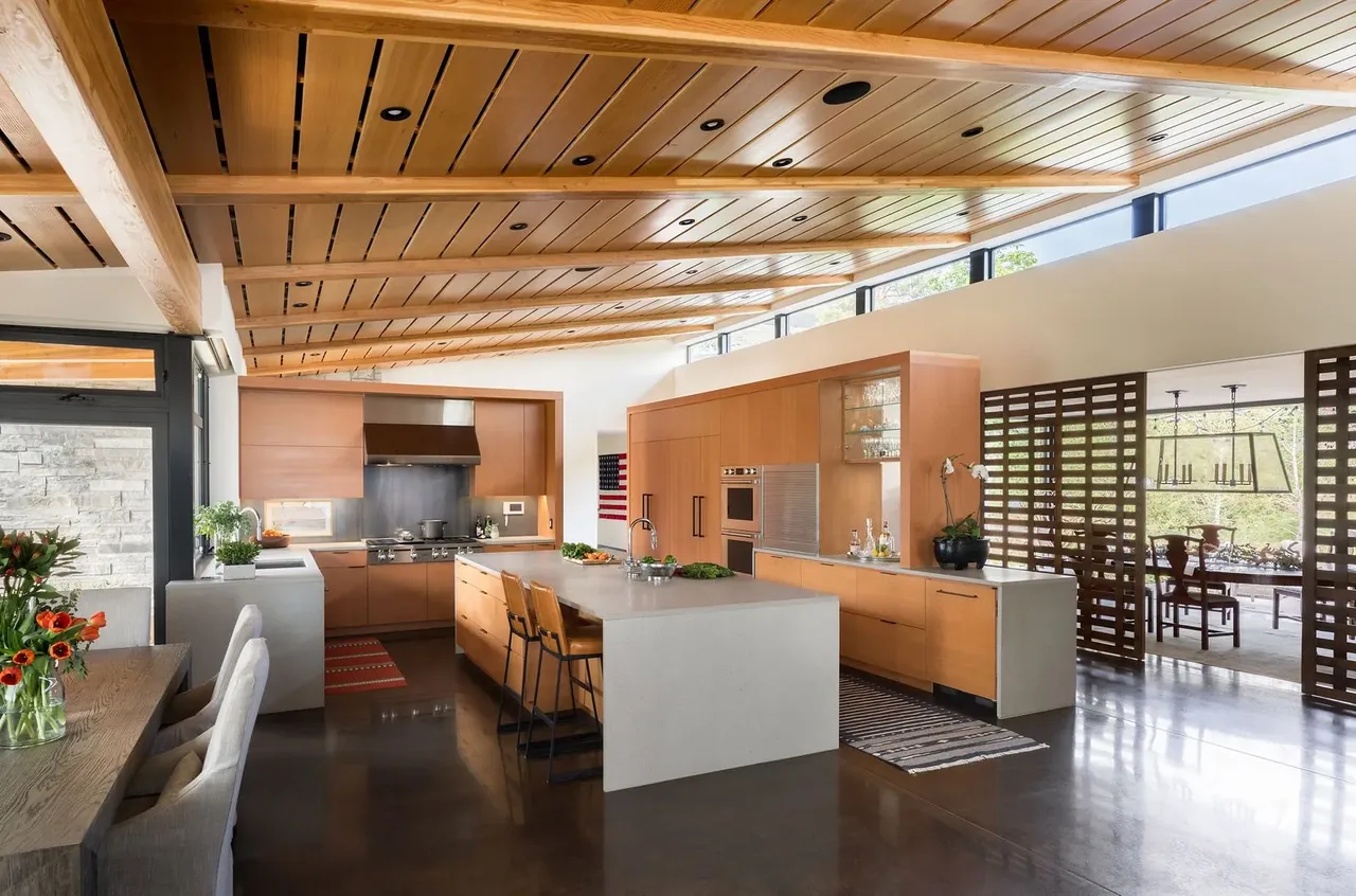 Kitchen in Cherry Residence by Semple Brown Design features wood cabinetry, concrete island, and wood ceiling beams.