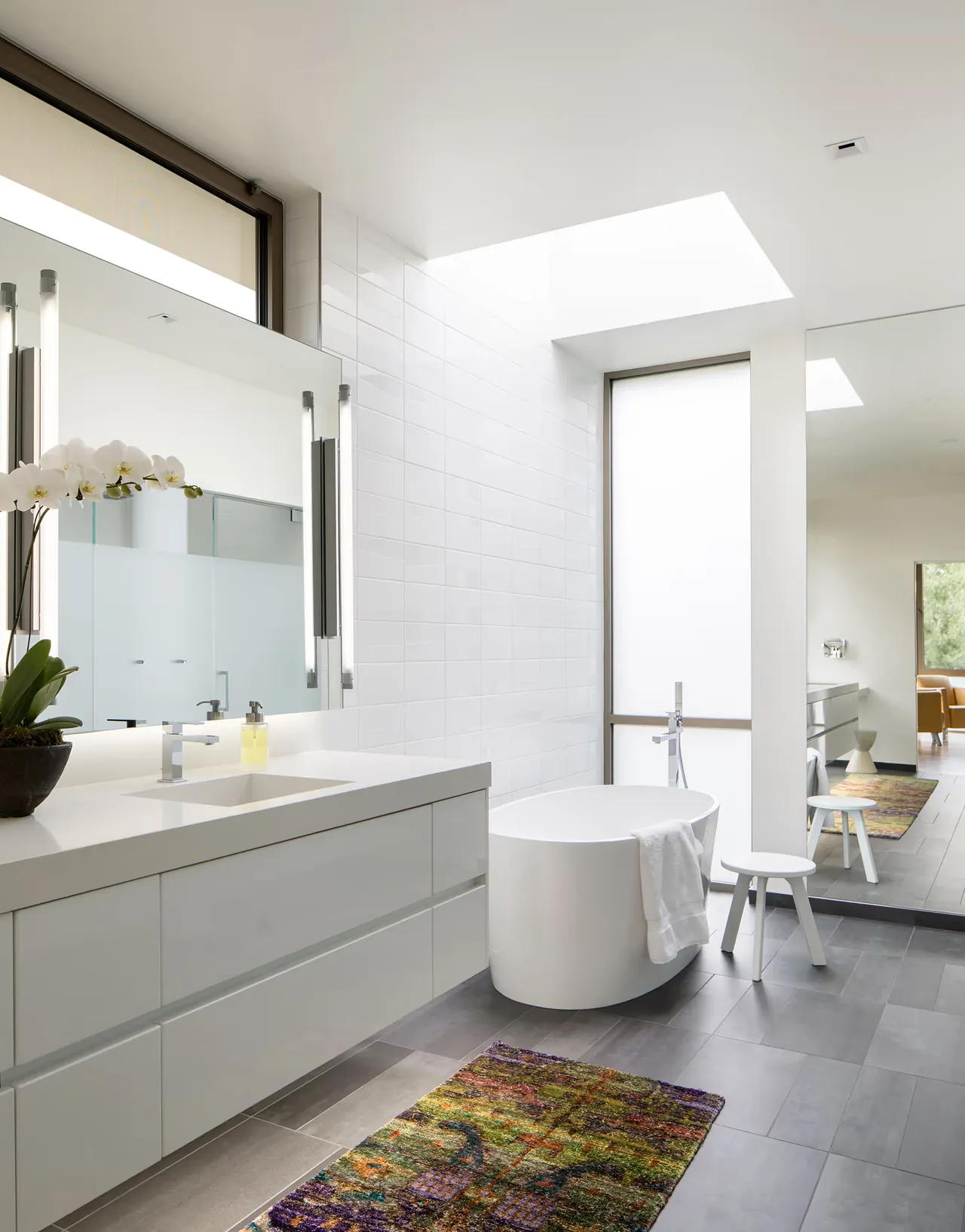 The bathroom of Duncan Residence features a freestanding tub, skylight, and modern white vanity with integrated sink.