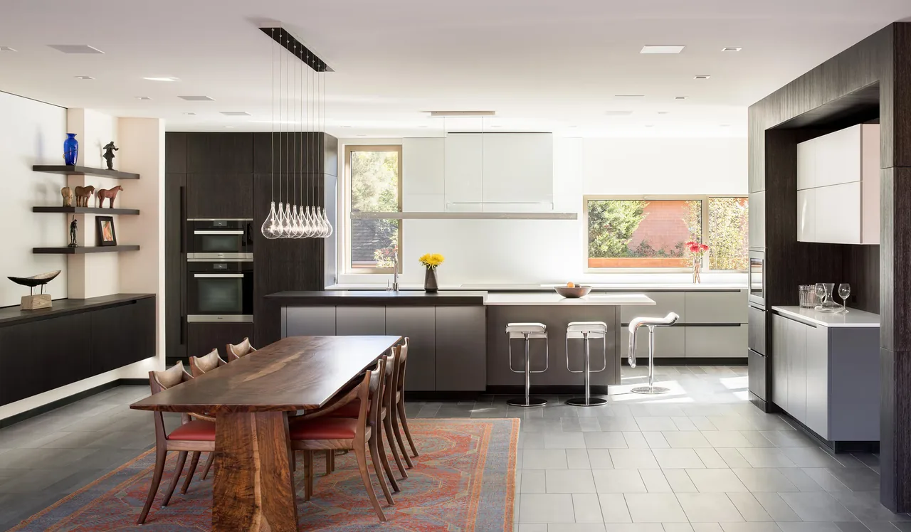 Open kitchen and dining room with dark wood cabinetry, a large wood table, and metal stools at the island.