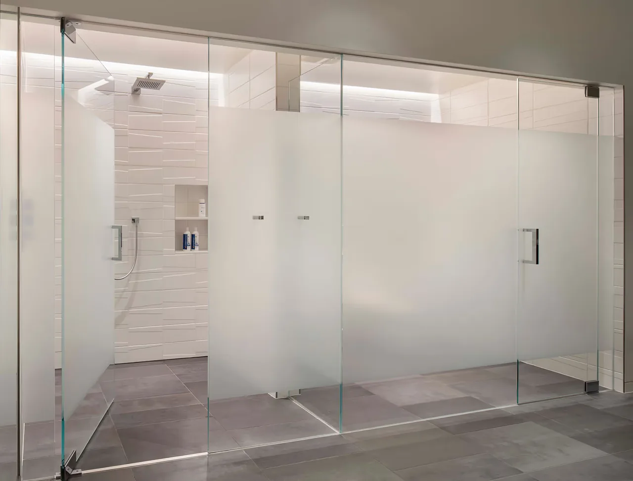 The Duncan Residence bathroom features a spacious walk-in shower with frosted glass doors and textured wall tiles.