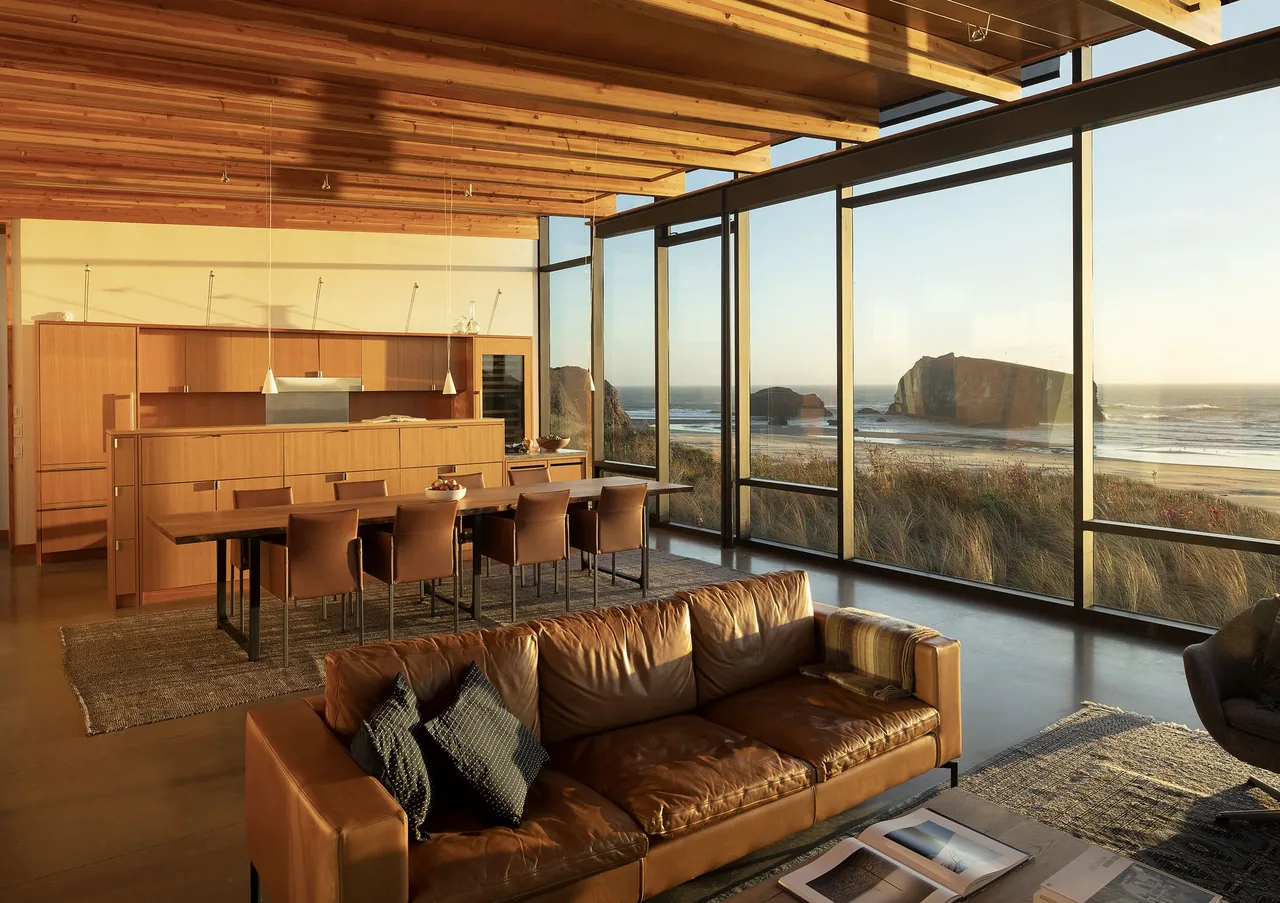 Open layout living and dining room with expansive floor-to-ceiling glass walls facing the beach.