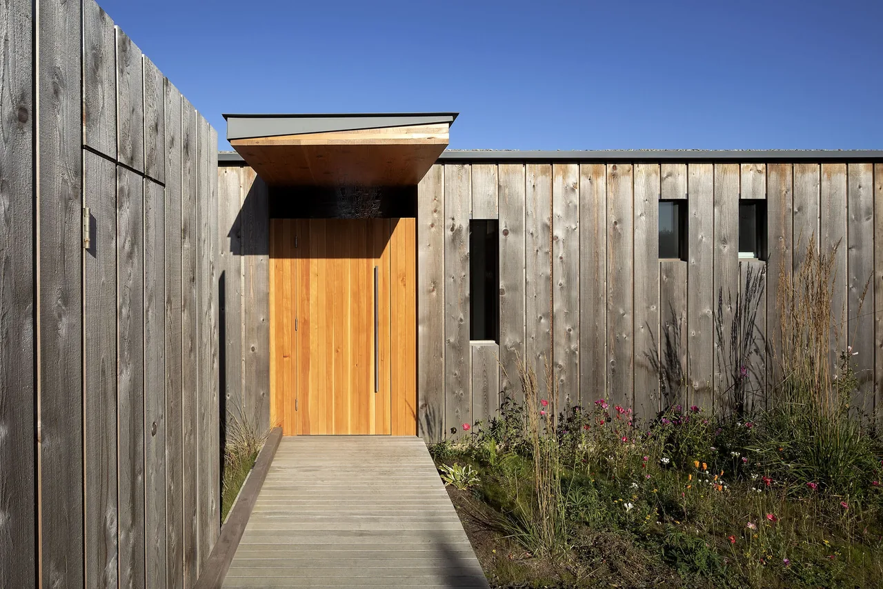 The front entrance of the Oregon Coast Beach House features vertical wood siding, a prominent wooden door, and a flat canopy.