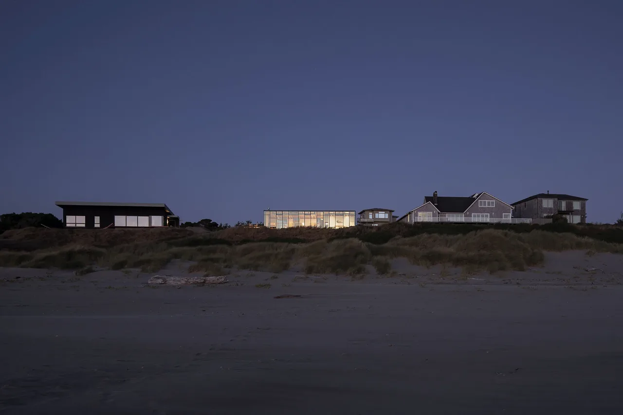 Distant view of a group of beach houses on the Oregon coast with dune vegetation in front during twilight.