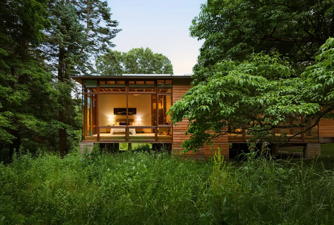 Modern residence with extensive floor-to-ceiling glazing set in a wooded landscape.