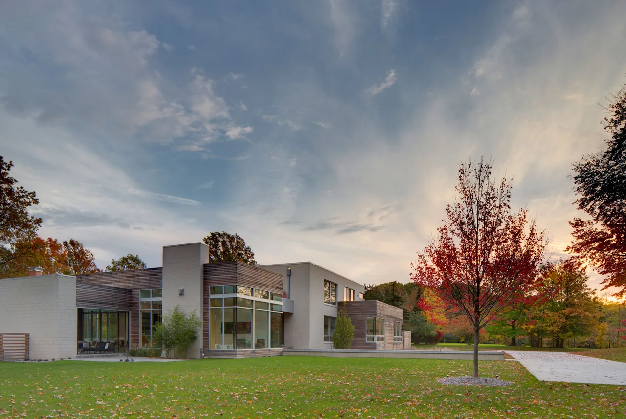 Exterior front view of a modern residence featuring concrete block and wood siding with floor-to-ceiling glazing.