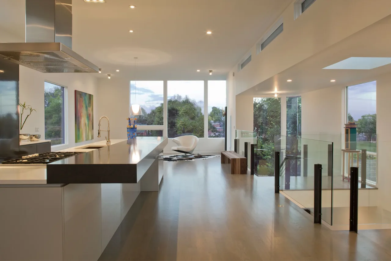 Interior view of a modern kitchen and living space featuring floor-to-ceiling windows and an island with a black countertop.