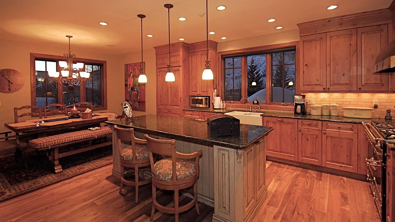 Kitchen and dining area featuring wooden cabinetry, a granite countertop island, and pendant lights.