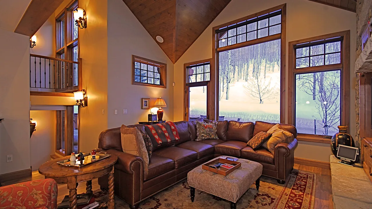 Living room features a vaulted wood ceiling and large windows with forest views.