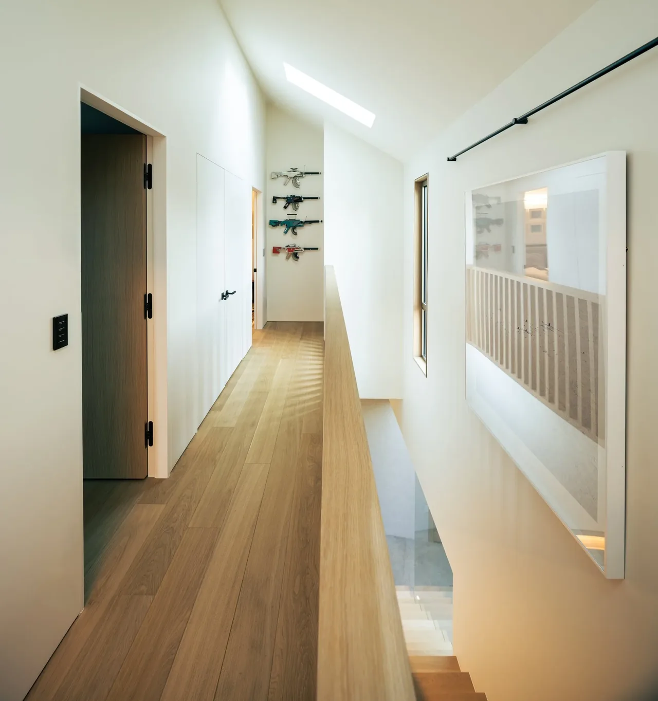 A bright upstairs hallway with skylight and wood flooring in a modern house.