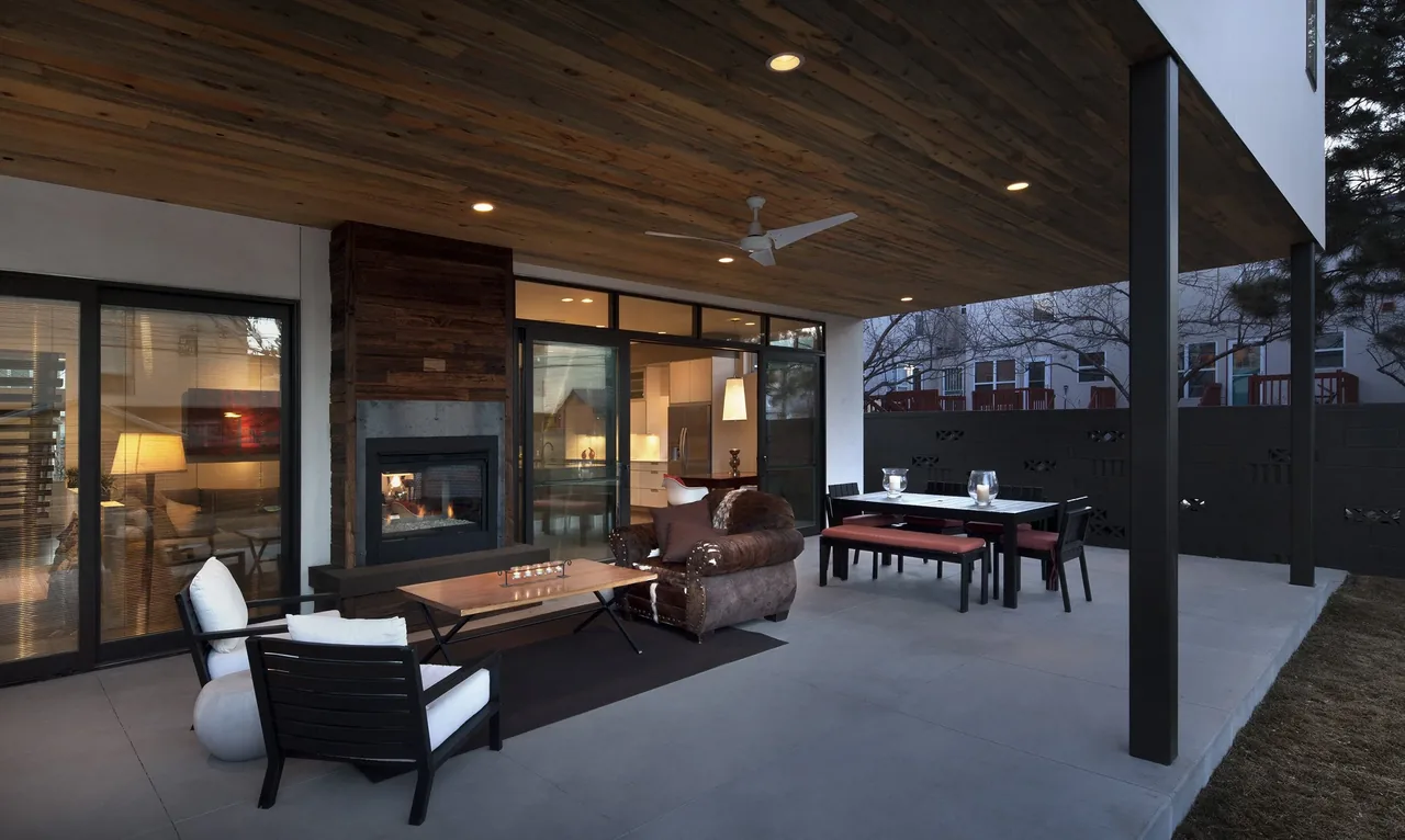 Covered patio with fireplace and outdoor seating connected to indoor kitchen area.