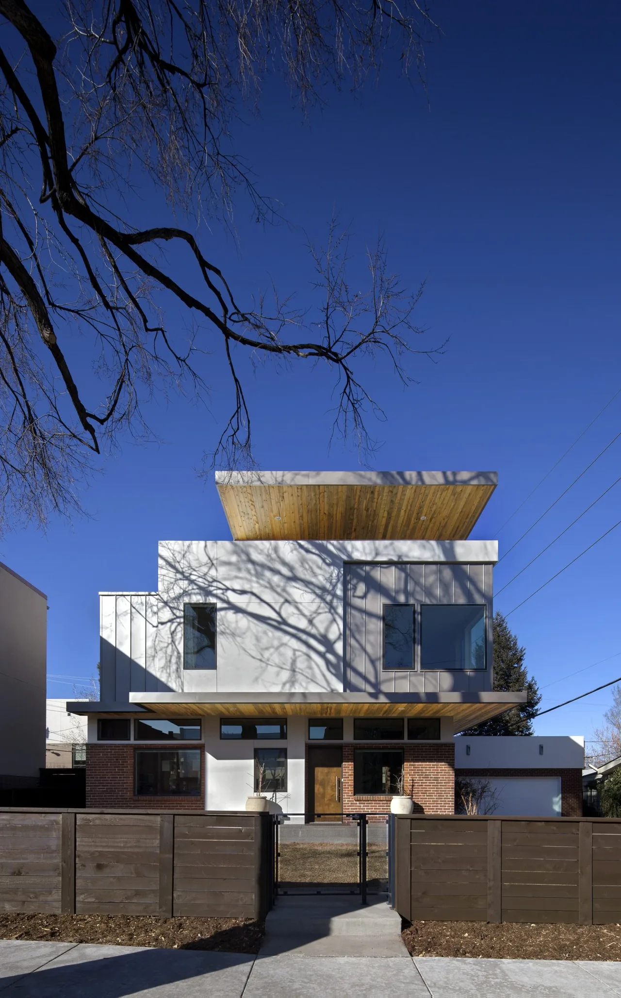 Front exterior of a modern two-story house featuring cantilevered upper level and brick and stucco materials.