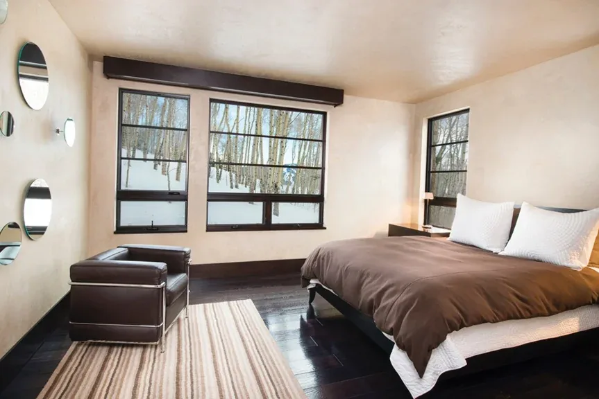 Bedroom interior featuring large metal frame windows and dark hardwood flooring.