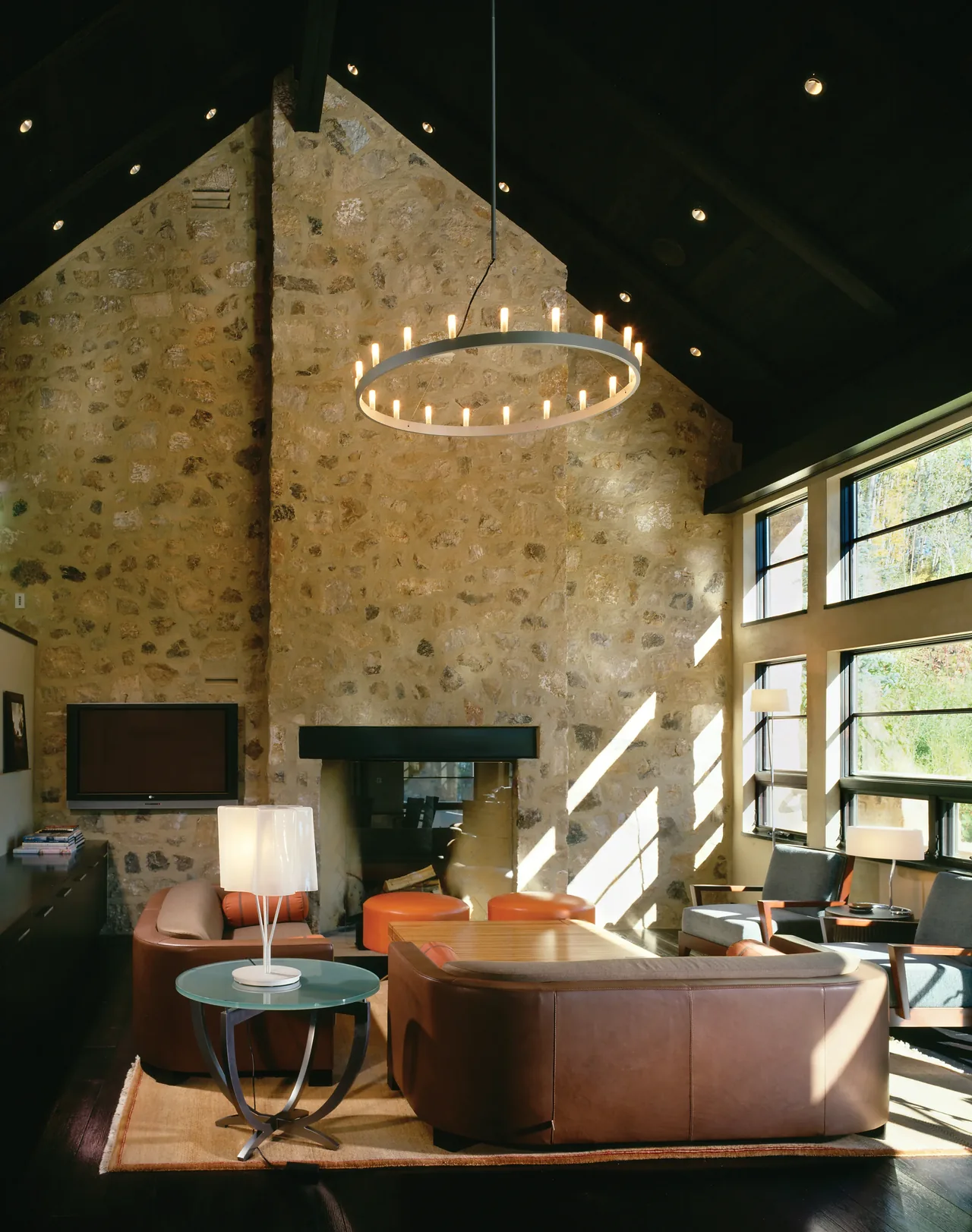 Living room featuring an arched ceiling, stone wall with fireplace, and floor-to-ceiling glazed windows with metal frames.