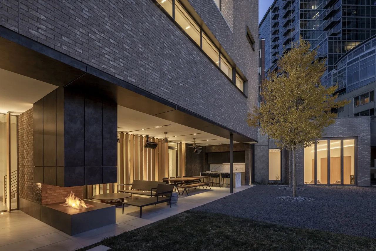 Private residence courtyard featuring a covered patio with outdoor fireplace and seating by 4240 Architecture in Denver.