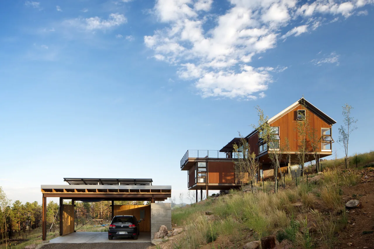 The Sunshine Canyon House features an elevated wood-paneled structure with an adjacent open carport on a hillside.