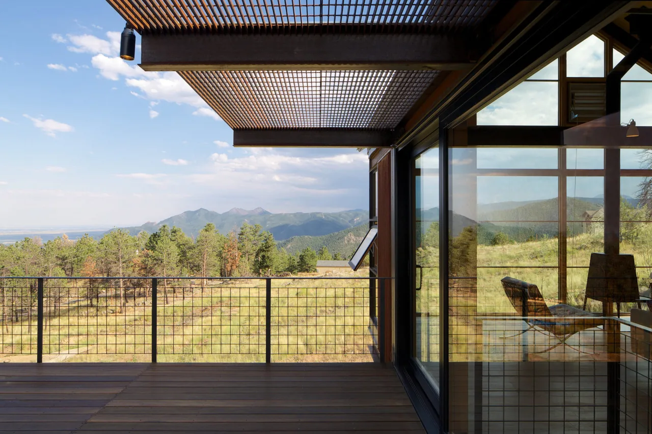 Metal railing balcony with wood decking and lattice overhead shade at Sunshine Canyon House overlooks mountain landscape.