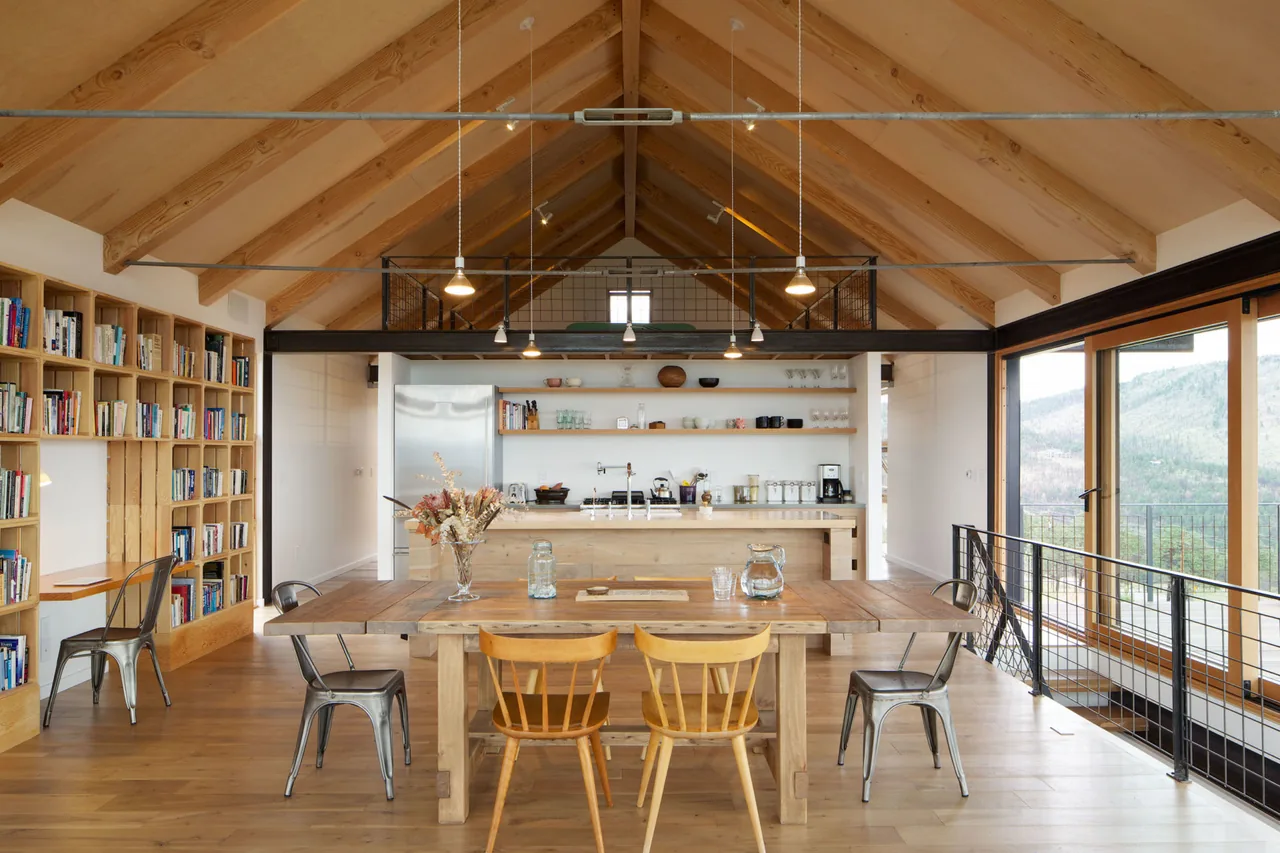 The Sunshine Canyon House kitchen and dining space feature a vaulted ceiling with exposed wooden beams and metal railing on the balcony above.