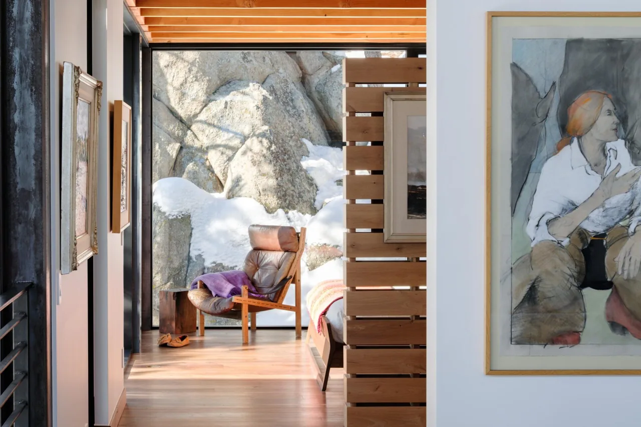 Hallway view into a seating nook with leather chair and large window showing a snowy rocky exterior at Goatbarn Lane.