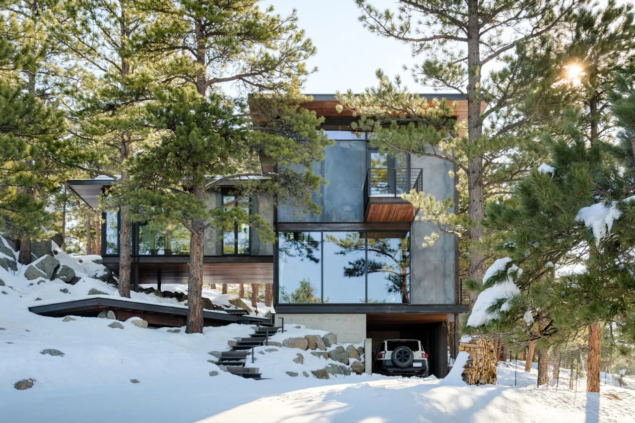Goatbarn Lane features a modern home with floor-to-ceiling glazing set in a snowy pine woodland near Denver.