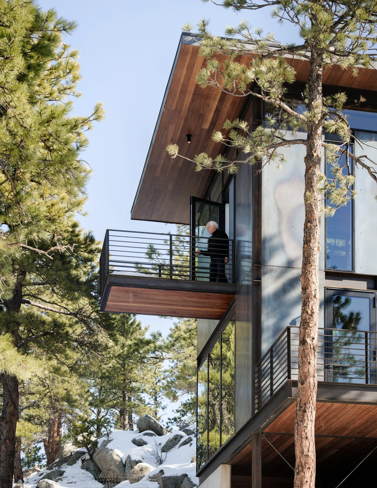The Goatbarn Lane project features cantilevered balconies with wood-paneled undersides in a natural wooded setting.
