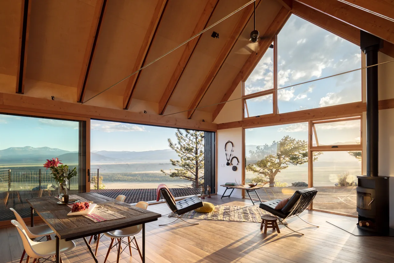 Interior of Big Cabin | Little Cabin showing exposed wood ceiling and large glass windows with mountain views.