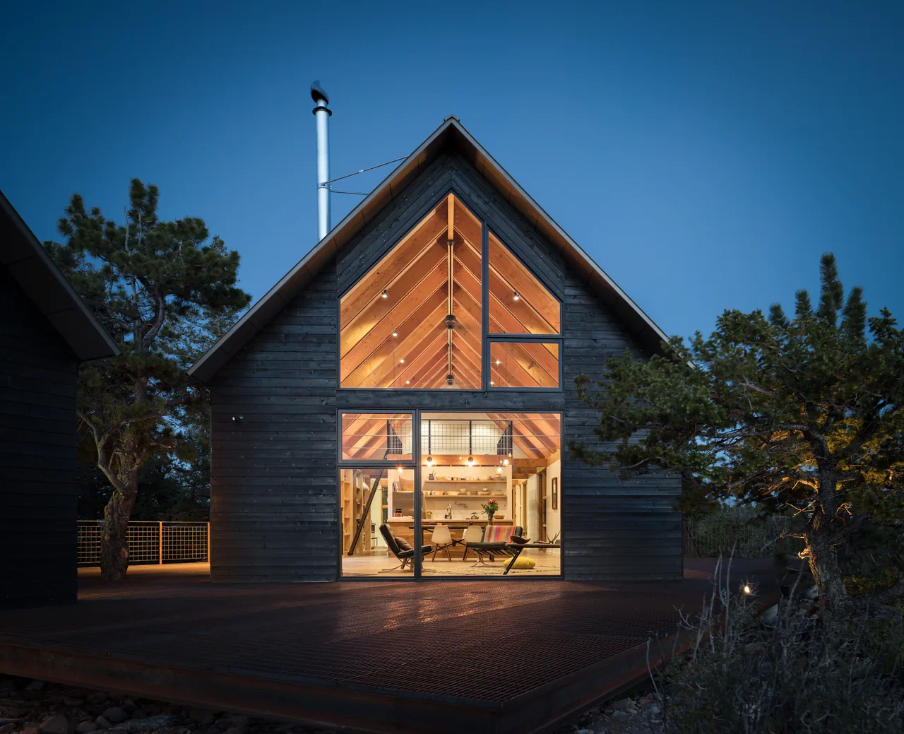 The Big Cabin features a dark wood exterior with large floor-to-ceiling glazing and a raised metal deck.