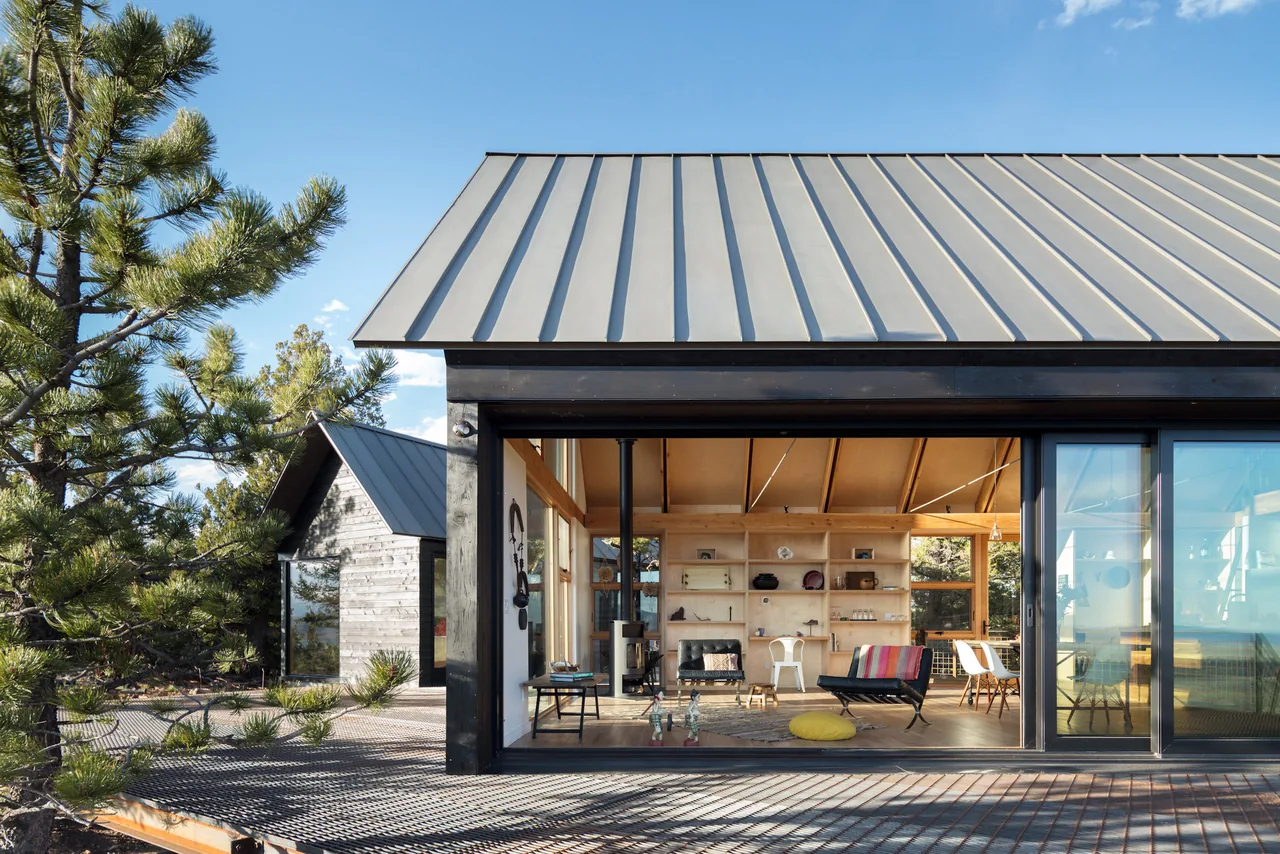 The Big Cabin | Little Cabin features a vaulted ceiling with exposed wood beams and an outdoor deck with wire mesh railing.