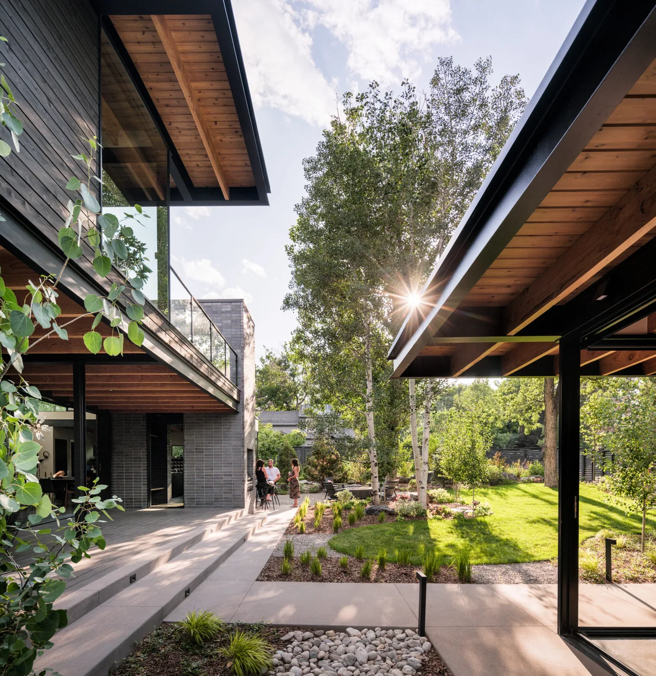 Shaded patio with glass railing and landscaped garden at Mariposa Garden House by Renée Del Gaudio Architecture.