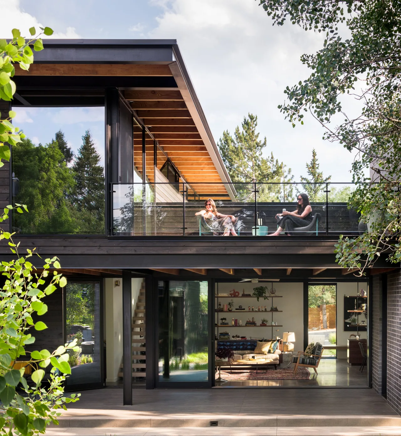 The balcony and living room of Mariposa Garden House with black window frames and wood ceiling beams.