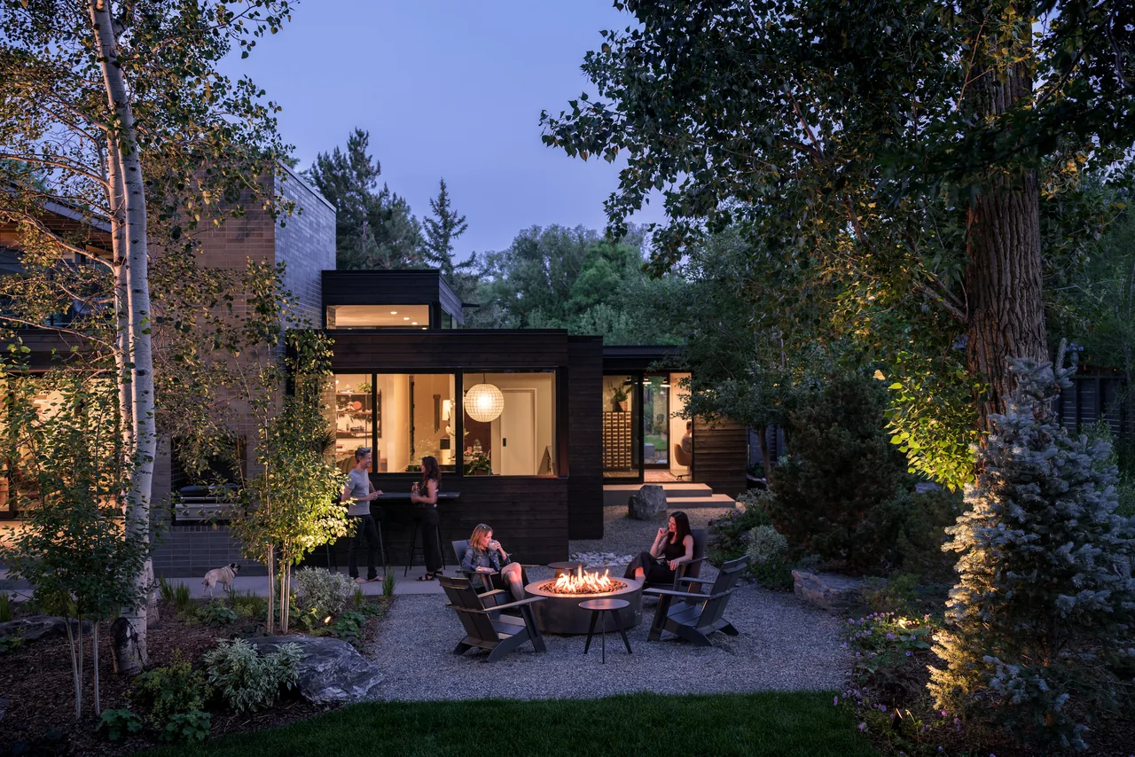 Evening outdoor seating area with a fire pit, surrounded by trees and modern garden landscaping at Mariposa Garden House.