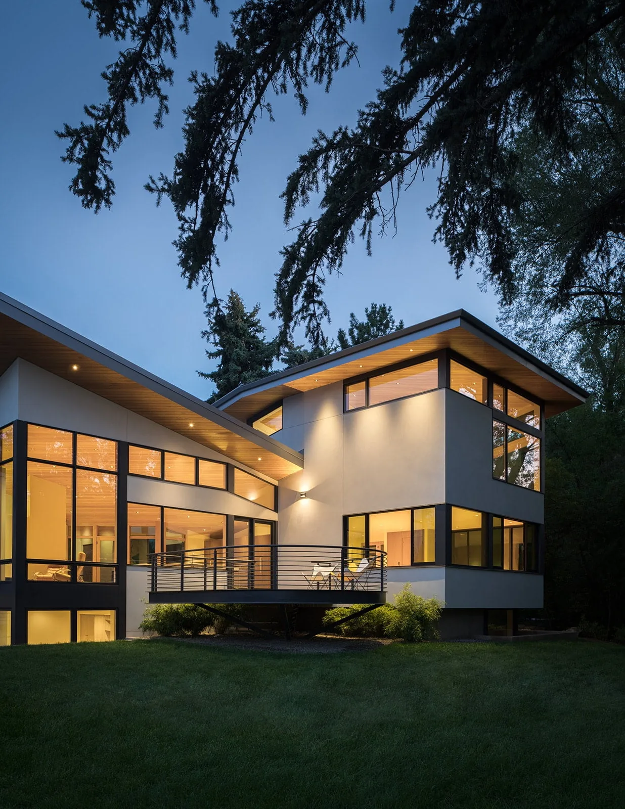 The Gregory Creek Residence features a modern design with extensive glazing and a cantilevered balcony with horizontal metal railing.