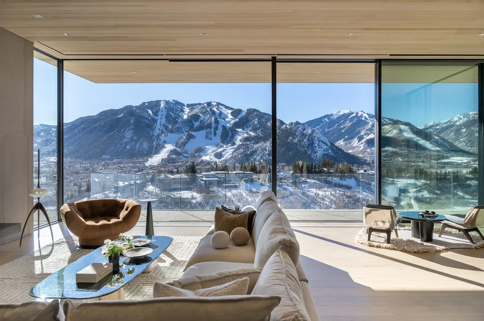 The Sunshine Mountain living room features floor-to-ceiling glazing with scenic mountain views and a minimalist wood ceiling.