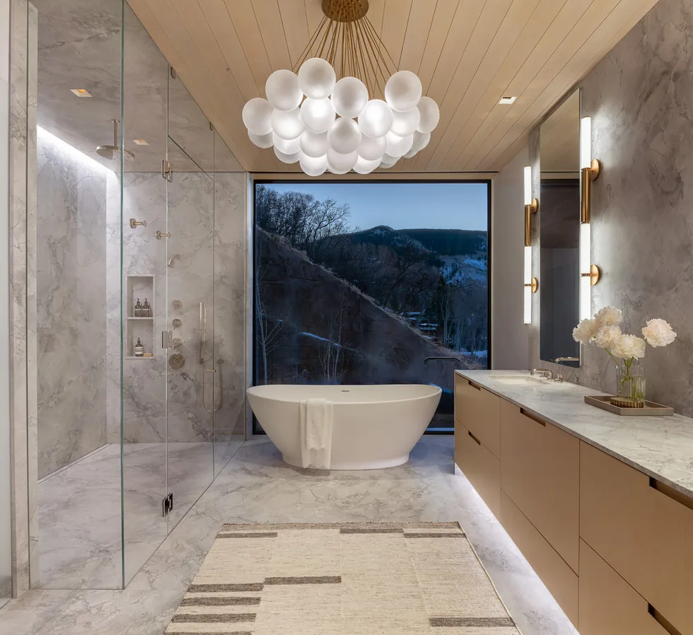 Bathroom featuring a freestanding tub with mountain views, glass shower, and wood ceiling in the Sunshine Mountain project by Charles Cunniffe Architects.