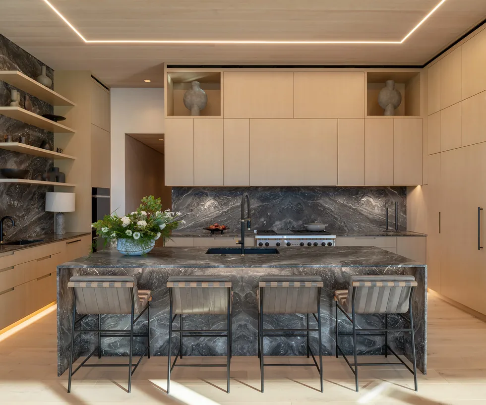 The kitchen features a striking marble island and backsplash paired with light wood cabinetry and built-in shelving.
