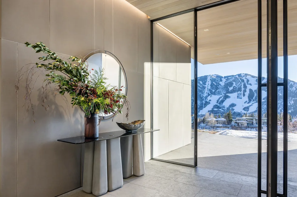 Sunshine Mountain entry features a concrete-base console table and a large sliding glass door opening to mountain views.