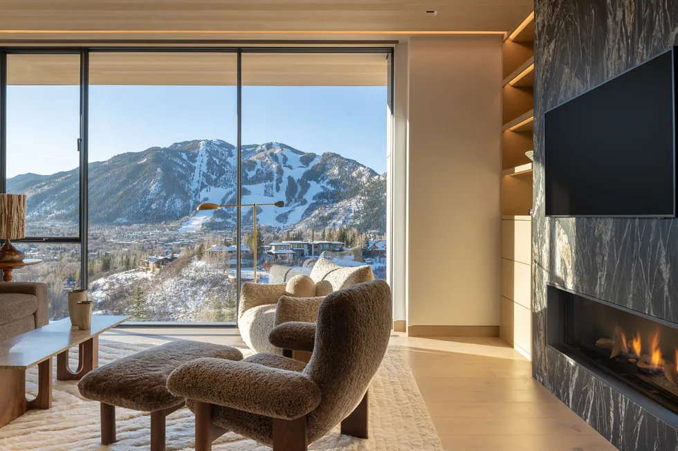 Sunshine Mountain living room features a floor-to-ceiling window framing a snowy mountain view, a modern fireplace, and cozy seating.
