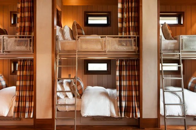 Cozy bunk beds with plaid curtains and wood-paneled walls in the bedroom at Elk Peak Ranch.
