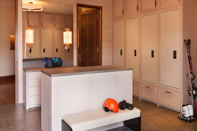 Mudroom features custom built-in lockers, a padded bench, and pendant lighting fixtures.
