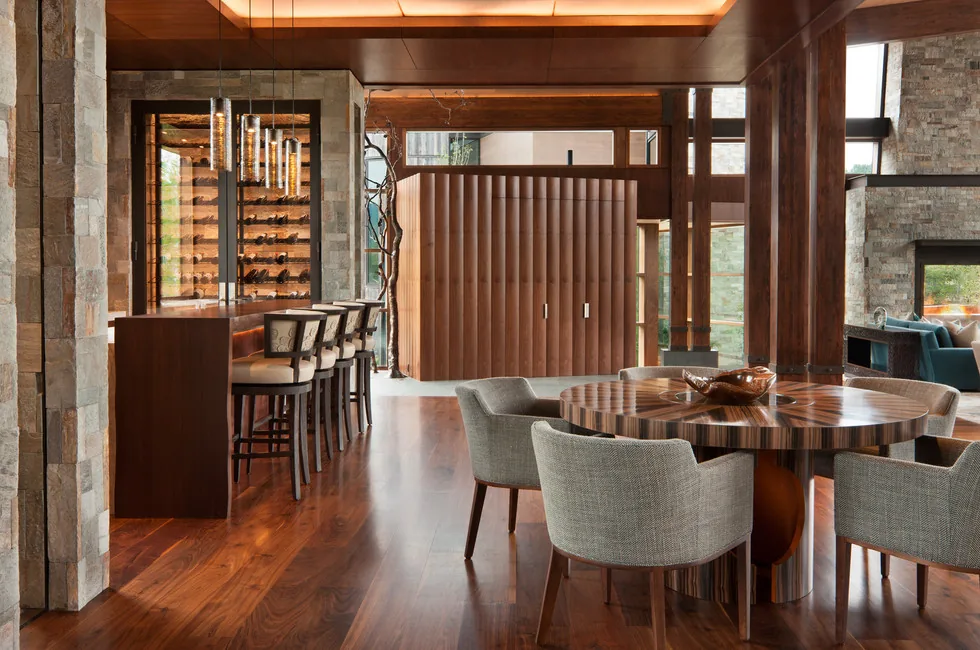 Dining and bar area inside Elk Peak Ranch featuring wood-paneled walls, stone columns, and built-in wine rack.