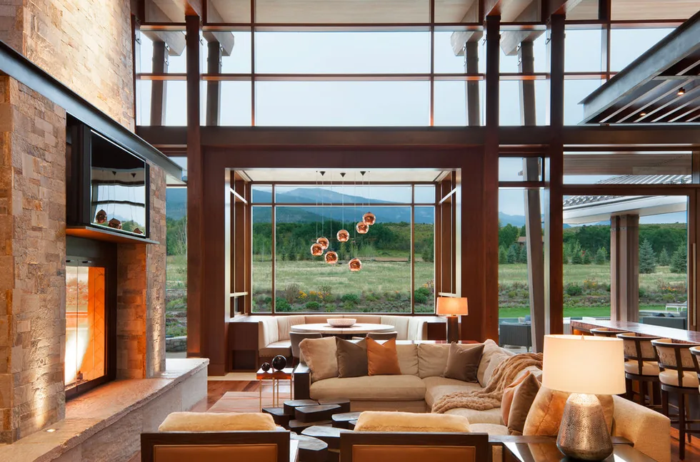 Elk Peak Ranch living room with floor-to-ceiling glazing and stone chimney by Charles Cunniffe Architects.